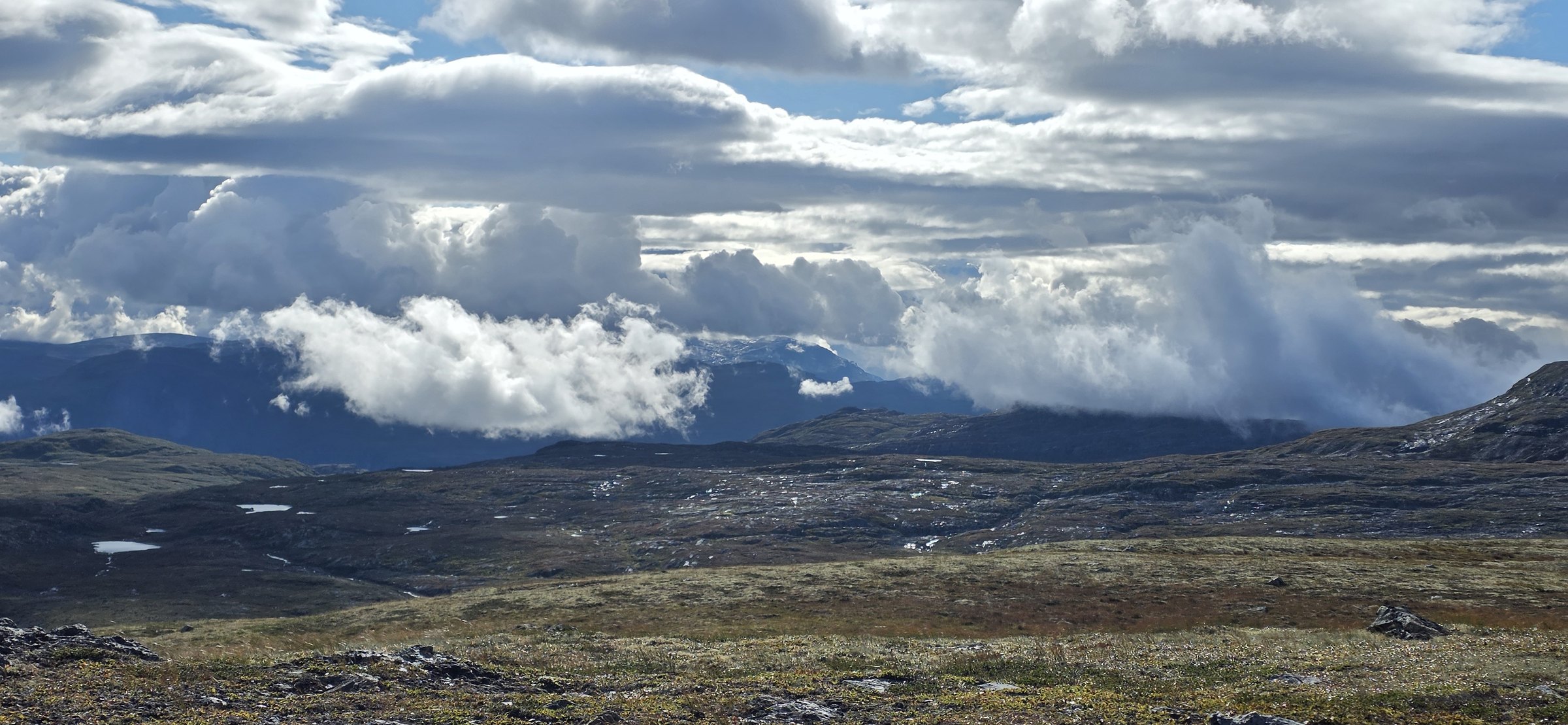 Weite Berglandschaft mit tiefen Wolken, Felsen und kleinen Seen – eine Aufnahme von OAHS